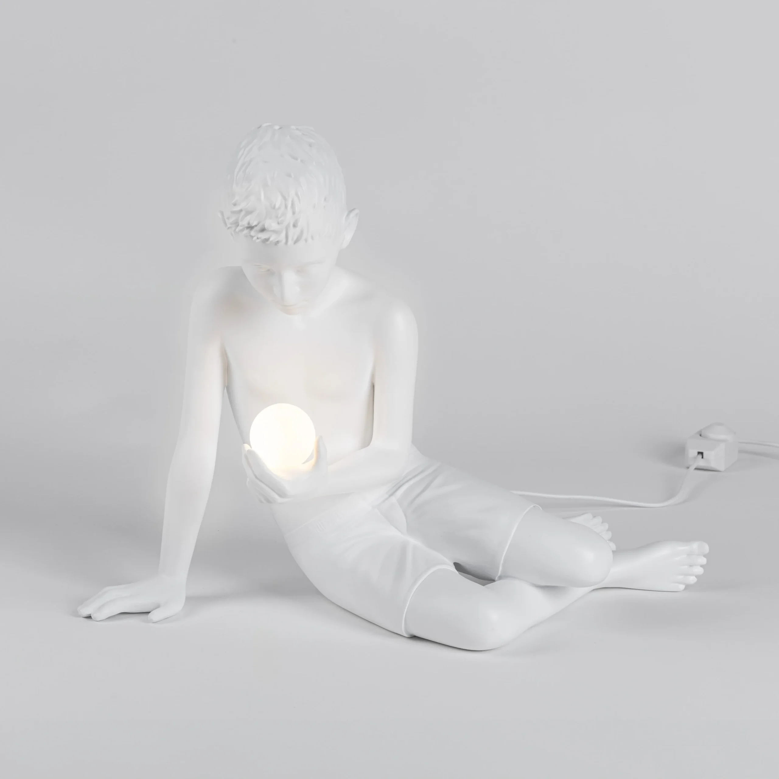 Innerglow Mini Boy accesa, figura seduta con luce sul corpo